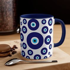 a blue and white coffee mug sitting on top of a wooden table next to a cookie