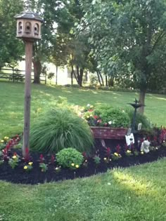 a garden with lots of flowers and plants in the grass next to a lamp post