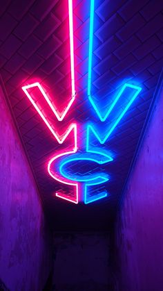 a neon sign is hanging from the ceiling in a dark room with pink and blue lighting