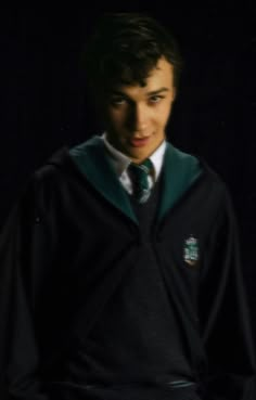 a young man wearing a green and black harry potter sweater with his hands in his pockets