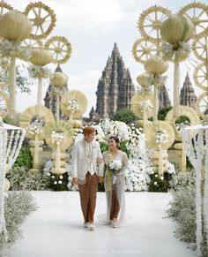 a man and woman are standing in front of an elaborately decorated area with white flowers