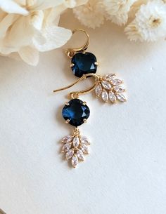 Gorgeous vintage inspired Art deco earrings. Faceted navy blue faceted cushion glass encased in gold setting; dangling below are intricate marquise cut cubic zirconia feather charm.  On gold plated brass settings and ear wires.  Simply stunning!! Total length: 43 mm Drop length: 33 mm Blue glass: 11*11 mm CZ drop: 16*12 mm Purchase over $40 enjoys free shipping! Coupon code 'freeshipping1'. Free Gift Wrapping on request - All items that are gift wrapped come in with a kraft box with raffia string and blank writing card.  Please leave a note if you need it upon ordering. Blue Gold Bridal Earrings, Art Deco Blue Drop Earrings, Blue Art Deco Wedding Earrings, Blue Art Deco Drop Earrings, Elegant Sapphire Jewelry With Ear Wire, Blue Art Deco Jewelry For Wedding, Blue Art Deco Jewelry For Party, Blue Art Deco Jewelry For Evening, Blue And Gold Earrings