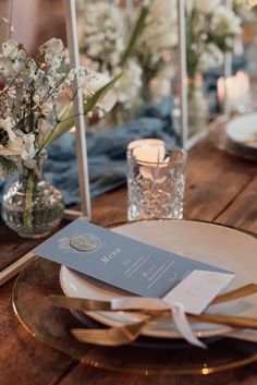 the table is set with plates, silverware and flowers in vases on it