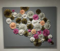 an abstract piece of art made out of paper flowers on a gray background with pink, gold and white petals