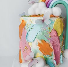 a multicolored cake with white frosting and rainbow decorations on the top layer