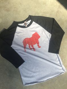 Go Dawgs! Unisex tri-blend raglan 3/4 sleeve t-shirt is screen printed with a distressed bulldog design. 3/4 sleeve, raw hem Style is unisex and runs slightly large.  Women may want to order one size down. Made of super soft material, this will be your go-to shirt to show your team spirit! Size   Body Width   Body Length  XS     16.5                 27   S      18                     28   M     19.5                  29   L      21                     30  XL     22.5                 31 Georgia Bulldogs Shirt, Bulldog Tshirt, Raglan Tshirt, Bulldog Shirt, Game Day Shirts, Georgia Bulldogs, Hem Style, Baseball Shirts, Bulldog