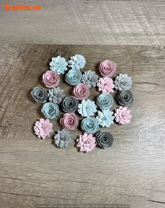 there are many small flowers made out of paper on the wooden table, one is pink and blue