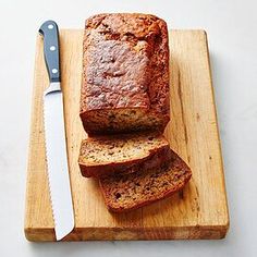 sliced loaf of banana bread on a cutting board with a knife next to the loaf