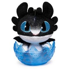 a black and white toy with blue eyes sitting on top of a plastic ball in the shape of a dragon