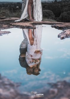 a bride and groom are reflected in the water