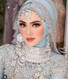 a woman wearing a blue hijab and headpiece with jewels on her face