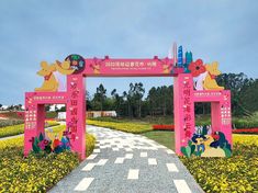 a pink gate with cartoon characters on it in the middle of a flower garden area