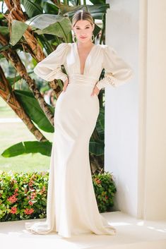 a woman in a white dress standing on a porch with her hands on her hips