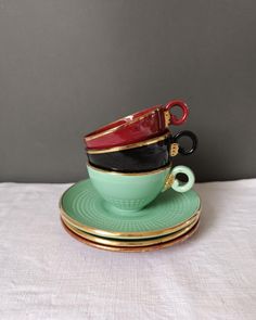 three cups and saucers stacked on top of each other with gold trimmings