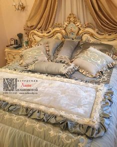 the bed is made up with many pillows and blankets on top of it, along with an ornate headboard