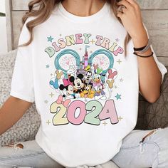 a woman sitting on a couch wearing a disney trip shirt