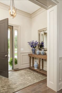 an entry way with vases and flowers on the table