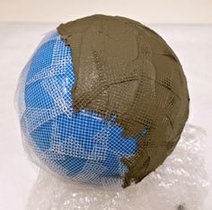 a blue and brown ball sitting on top of some plastic wrap around it's head