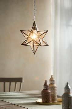 a star shaped light hanging from the ceiling above a table with two jars on it