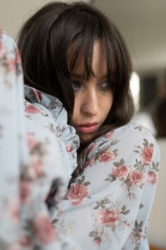 a close up of a person wearing a flowered shirt and looking at the camera