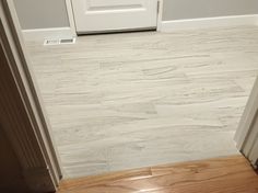 a white door is open in a room with wood floors and tile flooring on the walls