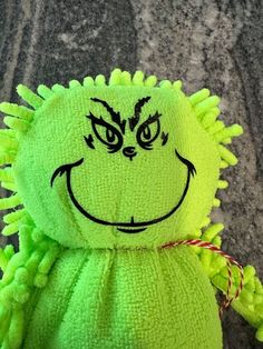 a close up of a stuffed animal with green hair and an evil grin on it's face