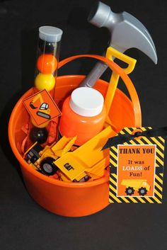 an orange bucket filled with construction items on top of a black table next to a thank card