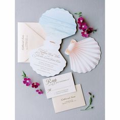 the wedding stationery is laid out with flowers and seashells