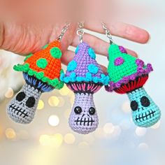 three crocheted keychains with skulls and mushrooms on them are being held by someone's hand