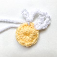 a crocheted ornament hanging from a white string on top of a table