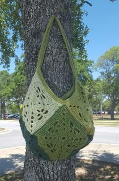 a crocheted bag hanging from the side of a tree