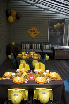 an outdoor dining area with yellow and black table cloths, plates and cups on it