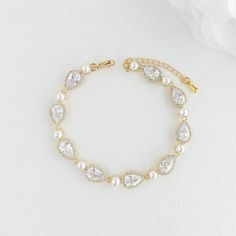 "A dainty and sparkling tear drop gold wedding bracelet for the bride with cubic zirconia and pearls. Adorned with shimmering crystals and lustrous pearls the bridal bracelet has a combination of halo set teardrop cubic zirconia crystals and small shell white pearls, finished off with a lobster clasp and an extension chain. Material used is 14k gold plated brass. Also available in rhodium/silver plated and rose gold plated finish. This bracelet is the perfect accessory for the bride, slim and el Gold Pearl Bracelet For Wedding, Pear-shaped Silver Bracelet For Weddings, Gold Cubic Zirconia Crystal Bracelet For Wedding, Elegant Pear-shaped Bracelets For Wedding, Elegant Pear-shaped Bracelet For Wedding, Dainty Gold Diamond Bracelet For Wedding, Gold Wedding Bracelet, Gold Bracelet Wedding, Gold Wedding Jewelry