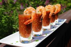 three glasses filled with shrimp on top of a white plate