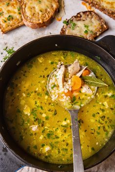 a bowl of soup with bread on the side and a ladle full of soup