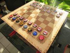 a wooden chess board with cupcakes on it sitting on top of a table