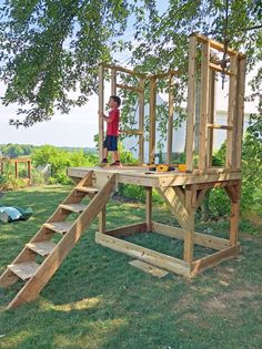 a little boy standing on top of a wooden structure in the middle of a field