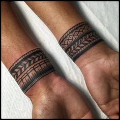 two men's wrist tattoos with designs on their wrists and arms, both in black ink