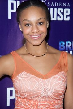 a woman in an orange and white dress posing for the camera