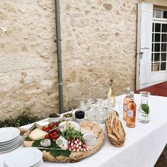 a table topped with lots of different types of food and drinks on top of a white table cloth