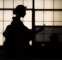 the silhouette of a woman standing in front of a window