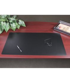 a desk with a pen and glasses on it next to a potted green plant