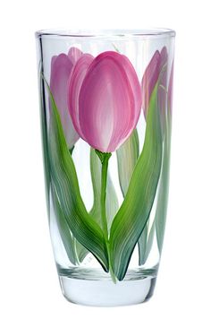 pink tulips in a clear glass vase with green leaves on the inside and bottom