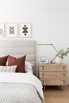 a bed with pillows and pictures on the wall above it, along with two nightstands