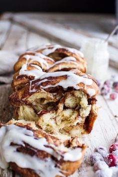 cinnamon roll with icing and cranberries on a wooden table