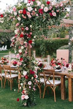 an outdoor table set up with flowers and greenery