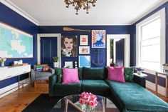 a living room with blue walls and green couches in front of a coffee table