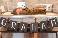 a baby is laying on top of a bed with the name graham hanging from it's side