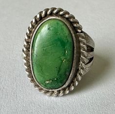 a wonderful, sturdy, beautifully made green turquoise and sterling artisan ring.  this is a southwestern piece, unmarked, with a wonderful stone.  the stone has some scratching and natural pits but no cracks.  band is very sturdy and split three ways at the shoulders, has reasonable wear.  fit for a slim finger. size:  just over 3.75 height of face:  3/4" width of inner band:  1/8" Artisan Rings, Beautifully Made, The Stone, Green Turquoise, Rings Statement, Silver Fashion, Favorite Jewelry, Statement Rings, Hippie Boho