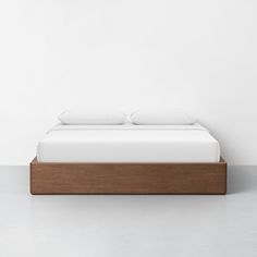 a bed with two pillows on top of it and a white wall in the background